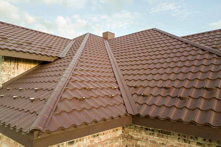 Detail of house roof structure covered with brown metal tile sheets.